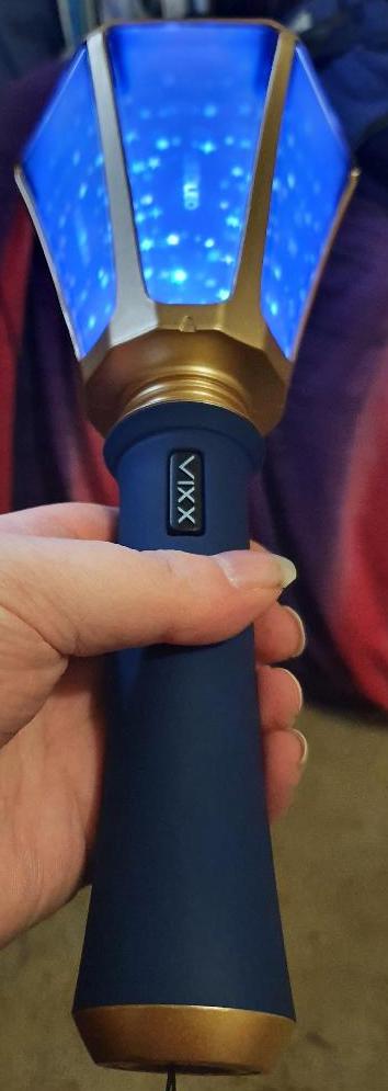 gold and navy blue lightstick held by the handle. the top part is turned on and looks like the stars